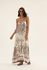 Mono largo de tirantes finos con estampado floral en tonos marrones sobre fondo blanco.