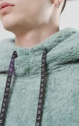 Hoodie verde agua de piel de corderito sintético con calce oversize y cierre central al estilo anorak. La capucha cuenta con cordón ajustable con la palabra Luxo.