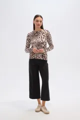 Sweater de tejido de punto, color crema, con estampado floral en tonos rosados y marrones. Presenta cuello redondo y mangas largas.