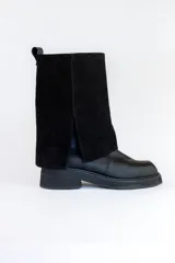 Bota de cuero negra con caña alta y detalle volcado en la parte superior. Taco bajo y puntera redondeada.