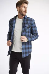 Sobrecamisa de viyela para hombre con estampado de cuadros en rojo y negro. Presenta cierre frontal con botones, bolsillos en el pecho con solapa y botón, y un interior capitoneado para mayor abrigo. Cuenta con un logo en grifa de cuero.