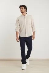 Camisa azul marino de lino y algodón, con cuello abotonado, manga larga con puños enrollados, bolsillo de parche en el pecho y cierre frontal con botones.