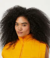 Chaleco cropped puffer color mostaza, con cuello alto y cierre frontal con cremallera.