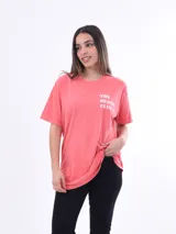 Remera color salmón con estampado frontal con la frase "The Beach Club" en letras blancas.