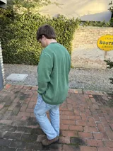 Buzo verde con cuello redondo y logo bordado en el pecho.