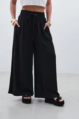 Pantalón palazzo negro de tencel con cintura elastizada y cordón ajustable.