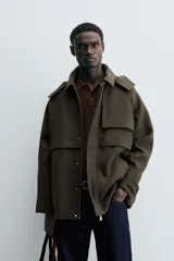 Parka verde oscuro confeccionada en tejido con lana, corte regular, cuello solapa con capucha desmontable, manga larga con puño ajustable, bolsillos de vivo en cadera y cierre frontal con cremallera oculta por solapa con botones a presión.