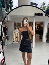 Pollera corta negra de ecocuero, con cortes y detalles de bolsillos grandes.