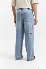 Pantalón jean celeste de corte carpenter, tiro medio, con presillas para cinturón y bolsillos laterales.