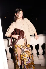Vestido largo con estampado de arabescos en tonos marrón, naranja y lila. Tiene escote halter, corte ajustado en busto y cintura, falda fluida con tajo delantero y está confeccionado en seda de algodón con lurex.
