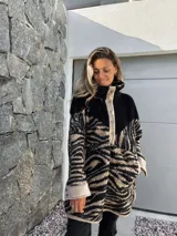 Buzo de polar con cuello alto, cierre de botones a presión y estampado de cebra en tonos beige y negro.