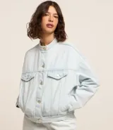 Campera trucker de jean celeste, con cuello alto, cierre con botones, bolsillos frontales y mangas largas.