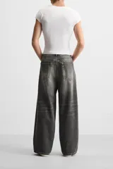 Pantalón de jean negro de corte amplio, con cinco bolsillos, efecto lavado y cierre frontal con cremallera y botón.