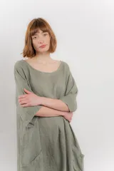 Vestido midi de lino con corte relajado y silueta fluida. Presenta escote redondo, mangas 3/4 y bolsillos laterales. Diseño minimalista y atemporal ideal para el verano.