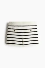 Minishort de corte ceñido en punto suave con cintura elástica de tiro alto y bolsillos delanteros decorativos con botón dorado de metal. Diseño a rayas horizontales blancas y negras.