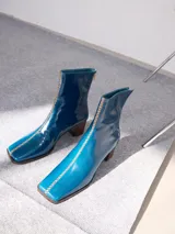 Botas de cuero azul con punta cuadrada, caña media y taco de madera. Cierre trasero con tirador y bordado en color contrastante en el empeine.