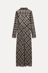 Vestido largo tipo camisero con estampado de cuadros en tonos marrón, negro y blanco. Tiene cuello solapa, mangas largas con puños abotonados, dos bolsillos de parche con solapa en el pecho y cierre frontal con botones a presión.