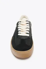 Zapatillas deportivas negras con detalles en cuero sintético y suela de goma color caramelo.