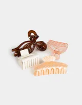 Set de cuatro broches para el pelo de diferentes formas y colores: uno con forma de moño rosa y rojo, uno rectangular color crema, uno transparente y uno con forma de media luna rosa marmolado.