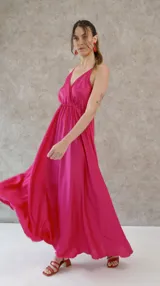 Vestido largo de seda color fucsia, con escote en V tanto en la parte delantera como en la espalda, y breteles finos.