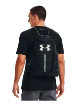 Mochila tipo bolso Under Armour negra con logo blanco estampado. Cuenta con cordones ajustables, funda aislante para botella de agua y tecnología UA Storm para repeler el agua.