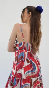 Vestido midi con estampado abstracto en tonos rojo, azul y marrón, con breteles finos y corte escalonado.