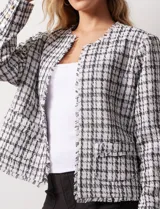Chaqueta en tejido tweed a cuadrillé blanco y negro, marca Nanette. Cuello a la base y abertura central. Delantera con bolsillos aplicados. Manga larga, puño con botones. Terminación desflecada. Forro interno.