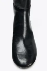 Bota de media caña color negro, de cuero, con punta redonda y tacón ancho.
