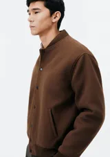 Campera bomber marrón con cierre de botones a presión, cuello mao y bolsillos laterales.