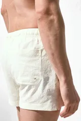 Short de baño color crema con textura de sirsaca, cintura elástica con cordón ajustable, bolsillos laterales, bolsillo trasero con cierre autoadherente y suspensor interior de malla.