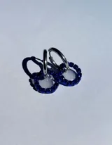 Par de aros colgantes con argollas doradas y dijes circulares de resina transparente con incrustaciones de strass de colores. El dije mide aproximadamente 1.5cm de diámetro.