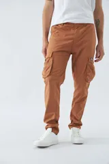 Pantalón cargo color marrón, corte slim, con cierre y botón en la cintura, pasacintos y bolsillos cargo con botones.