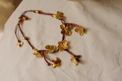 Collar corto con cordón de algodón color menta y flores de bronce.