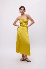 Vestido midi amarillo de satén con escote halter, trenzas en cuello y cintura, cut-outs laterales y falda recta.