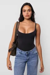 Body negro ajustado al cuerpo, con escote redondo y breteles finos. Tiene broches snap en la entrepierna y logo estampado en la espalda.