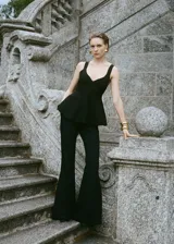 Top negro de tejido de punto fino con corte peplum, cuello de pico, tirantes anchos y espalda descubierta.