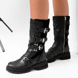 Bota de cuero color marrón con caña media, suela de goma negra, cierre lateral y hebillas ajustables. Presenta detalle trenzado en el talón.