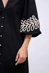 Vestido blanco de lino con escote en V, mangas cortas abullonadas y bordados florales en beige en mangas y ruedo.