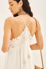 Vestido corto blanco de algodón con breteles finos regulables y terminación de flecos. Presenta bordados a contratono en delantero, espalda y ruedo. Está forrado.