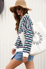 Sweater oversize de punto con rayas horizontales en colores azul, verde y lila. Tiene cuello polo blanco con cartera de botones.