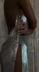 Vestido corto plateado de malla metálica con escote pronunciado en V y tirantes finos de cadena. Presenta aberturas laterales pronunciadas.