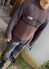 Sweater marrón con rayas horizontales azul marino, cuello redondo y parche con logo bordado en el pecho.