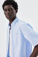 Camisa celeste de algodón Oxford con cuello abotonado, manga corta, bolsillo de parche en el pecho y corte regular.