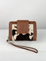 Billetera pequeña de cuero marrón con aplique de cuero vacuno blanco y negro. Cierre con cremallera y correa de muñeca.