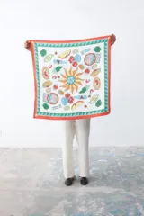 Pañuelo cuadrado de tela fina color blanco con estampado de motivos gastronómicos y borde con diseño geométrico en rojo, verde y celeste.