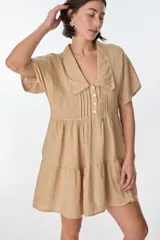 Vestido corto celeste de lino, con cuello tipo polo con detalle de puntilla, mangas cortas y falda escalonada con volantes.