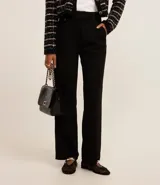 Pantalón de vestir negro de corte wide leg, confeccionado en crepé. Presenta cintura con trabillas, detalle de solapa con botón y bolsillos laterales.