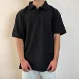 Chomba negra de tejido ottoman con cuello clásico, tapeta de dos botones y mangas cortas.