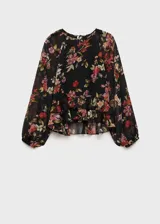 Blusa de mujer con estampado floral en tonos rojos, rosas y verdes sobre fondo negro. Tiene cuello redondo, mangas largas abullonadas, volantes en el bajo y cierre de lazo en el cuello.