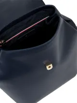 Mochila de poliuretano color azul marino con silueta estructurada y cierre de solapa con broche magnético. Presenta un asa de mano superior y correas de hombro ajustables con cinta distintiva de Tommy Hilfiger. El frente lleva un monograma TH metálico en dorado.